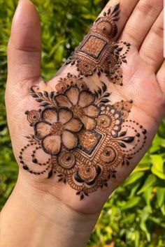 a person holding up their hand with henna on it