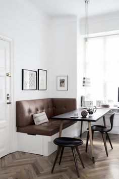 a table with two chairs and a bench in front of a door that has pictures on the wall above it