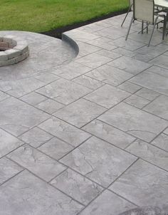 an outdoor patio with concrete pavers and fire pit in the center, surrounded by grass