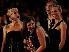 three women in black dresses are laughing and posing for the camera at an awards event