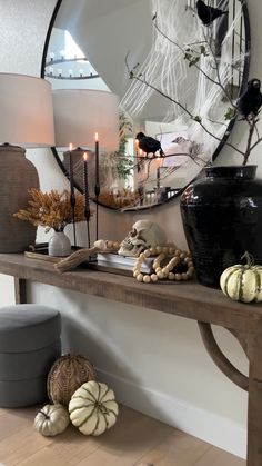 a table with candles, pumpkins and other items on it in front of a mirror