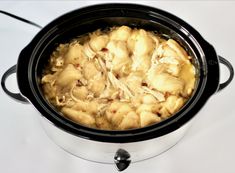 a crock pot filled with food sitting on top of a white counter next to a knife