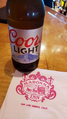 a bottle of soda sitting on top of a table next to a piece of paper