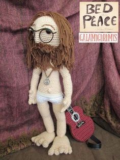 a crocheted stuffed animal with glasses and beard holding a red guitar in front of a purple background