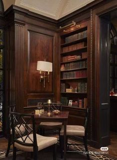 an office with wooden paneling and leather chairs, a desk in front of a large bookcase