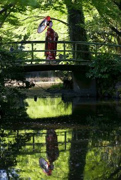 a man standing on a bridge over a body of water with a bird in the foreground