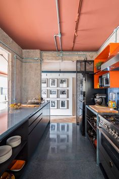 a kitchen with an orange ceiling and black counter tops, along with stainless steel appliances