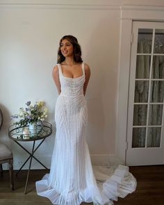 a woman in a white dress standing next to a table