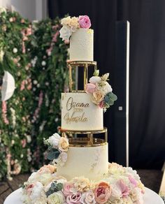 a three tiered wedding cake with flowers on the bottom and gold trimmings