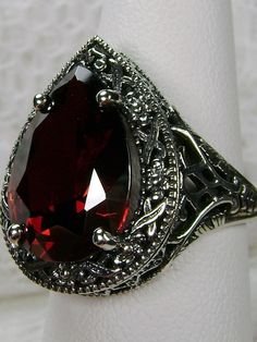 Red Garnet CZ Gemstone Teardrop RingTear Vic Design#D28 Inspired by Victorian and Art Deco designs, this high-quality filigree ring is handcrafted in sterling silver. This teardrop ring is set with an 8 carat pear cut flawless red CZ (Cubic Zirconia) gemstone. The gem is 16mm (~5/8") x 12mm (~1/2"). The gorgeous stone has a lovely vibrant color. The inside of the band is marked 925 for sterling silver. Notice the beautiful filigree of the silver setting. This is a ring with beauty and grace. The Classic Teardrop Ruby Ring For Formal Occasions, Formal Ruby Teardrop Ring, Formal Teardrop Jewelry With Intricate Design, Elegant Red Filigree Ring As Gift, Classic Teardrop Jewelry With Intricate Design, Elegant Teardrop Ruby Ring Gift, Formal Teardrop Ruby Ring, Victorian Drop Jewelry Gift, Classic Teardrop Ruby Ring For Gift