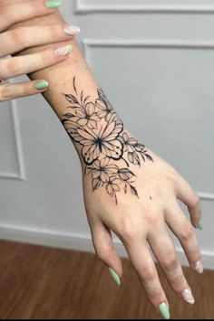 a woman's hand with black and white flowers tattooed on the left side of her arm