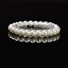 three bracelets with white pearls on black background