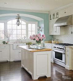 a large kitchen with white cabinets and an island in the middle, along with wooden floors