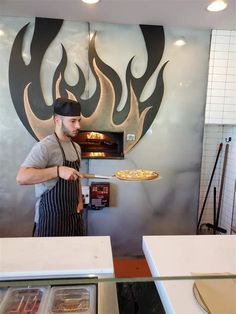 a man standing in front of an oven with pizzas cooking on top of it