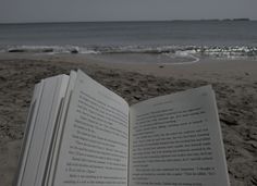 an open book sitting on top of a sandy beach