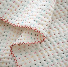 a white blanket with red, yellow and blue dots on it's edges is folded up