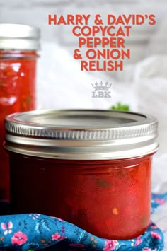 two jars filled with red liquid sitting on top of a blue cloth next to each other