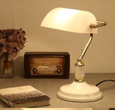 a table with a lamp, books and an old radio on the counter top next to it