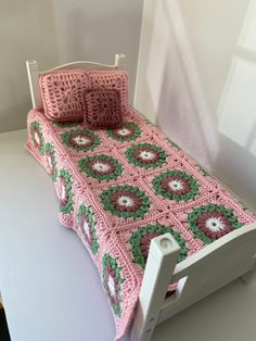 a crocheted bed with pink and green bedspread on top of it