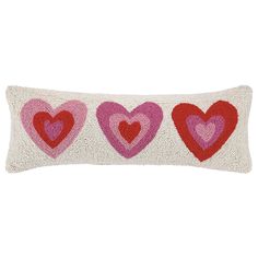 three hearts on a white pillow with pink, red and pink trims in the middle