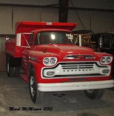 an old red truck parked in a garage