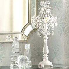 a white table topped with a glass vase filled with flowers next to a wall mounted mirror