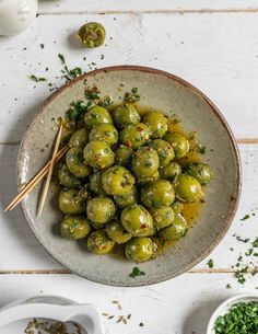 a bowl filled with brussel sprouts and chopsticks on top of a white table