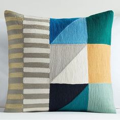 a multicolored patchwork pillow on a white couch with pillows in the background