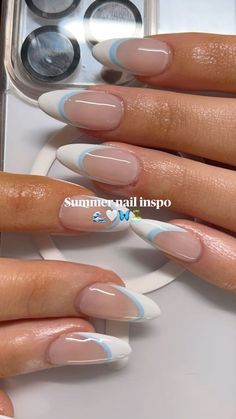 a woman's hand with some white and blue nail polishes on her nails