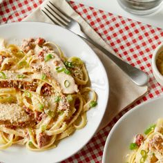 a plate of pasta with sauce and green onions on a red checkered tablecloth