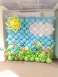 balloons are arranged in the shape of clouds, flowers and a sun on a wall