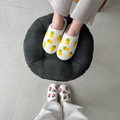 two people wearing slippers standing next to each other on a chair cushion with pineapples on them