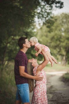 a man and woman holding a baby in the air while standing next to each other