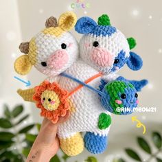 two stuffed animals are being held by someone's hand in front of a plant