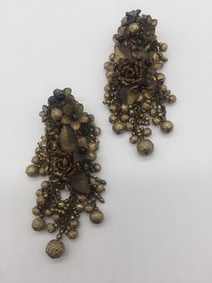 Chandelier earrings in Antique Gold with clusters of rich, gorgeous flowers and golden foiled glass beads. Constructed with glass beads and hand painted resin flowers. This is a quality piece of jewelry that will last a life time. Created by designer Colleen Toland who has been creating her unique style of vintage jewelry for more than 30 years. Earrings measure .5 inches by 2 inch. All metal components are nickel free and are plated in antique gold. All our post earrings are hypoallergenic. IF Elegant Gold Flower Earrings With Dangling Beads, Vintage Gold Beaded Earrings For Party, Gold Vintage Beaded Earrings For Party, Gold Embellished Earrings Gift, Gold Flower Earrings For Festive Occasions, Unique Gold Flower Earrings For Wedding, Gold Beaded Flower Earrings For Party, Gold Flower-shaped Jewelry With Dangling Beads, Gold Flower-shaped Earrings With Dangling Beads