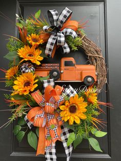 a wreath with sunflowers and an orange truck is hanging on the front door