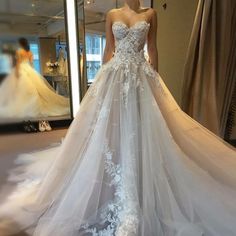 a woman is standing in front of a mirror wearing a wedding dress with flowers on it