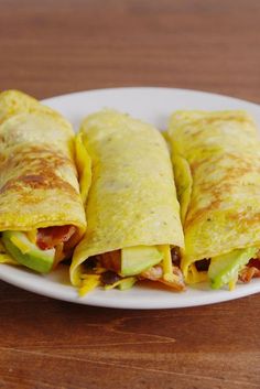 two burritos on a white plate sitting on a wooden table