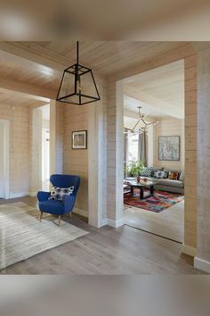 a living room with wood paneling and blue chair in the middle of the room