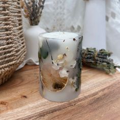 a white candle sitting on top of a wooden table next to dried flowers and plants