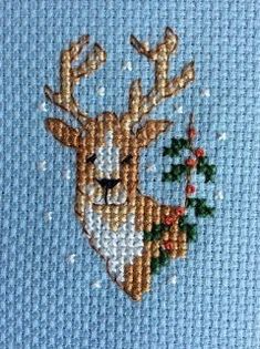 a cross stitch christmas card with a deer and holly