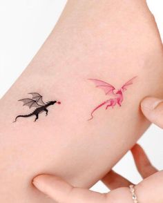 a woman's arm with two small tattoos on it, one is pink and the other is black