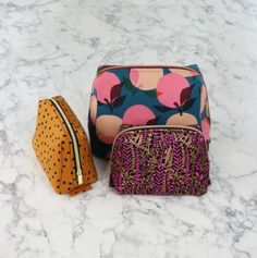 three different colored bags sitting on top of a marble countertop next to each other