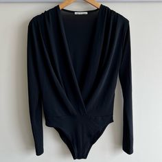 a black bodysuit hanging up on a hanger in front of a white wall