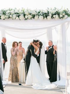 a bride and groom kissing under the chute at their wedding ceremony on the beach