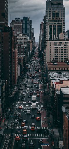 a city street filled with lots of traffic and tall buildings under cloudy skies in the distance