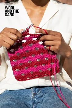 a woman is holding a pink crochet bag and knitting it with her hands