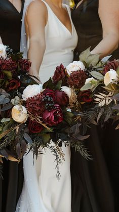 three bridesmaids holding their bouquets with red and white flowers in the middle