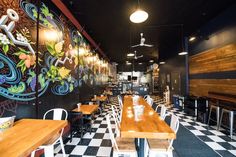 the interior of a restaurant with checkered flooring and walls painted with colorful designs