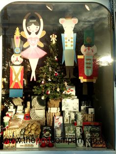 a window display with paper dolls and christmas trees in it's windowsills